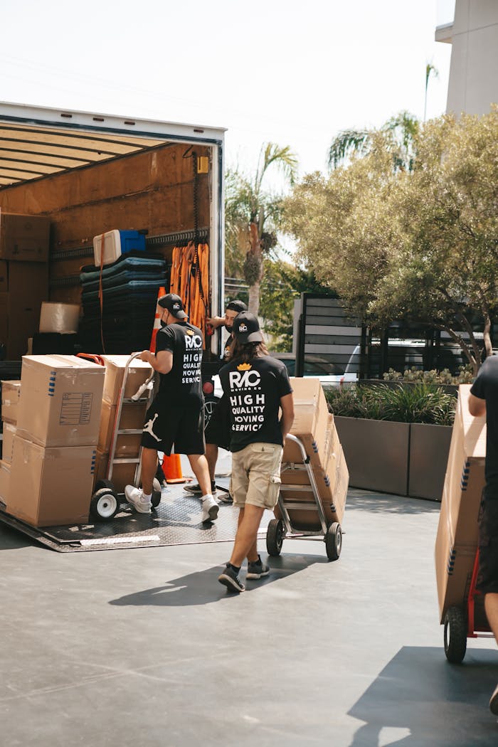 about-01 Movers loading boxes into a truck on a sunny day, capturing a busy urban scene.